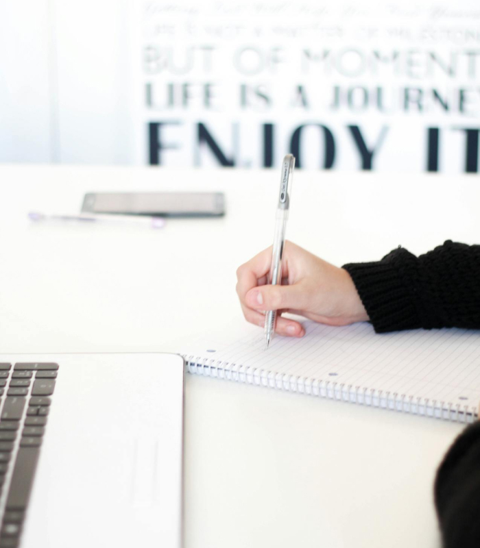 Designing fabric collections: Hand writing notes near laptop on desk