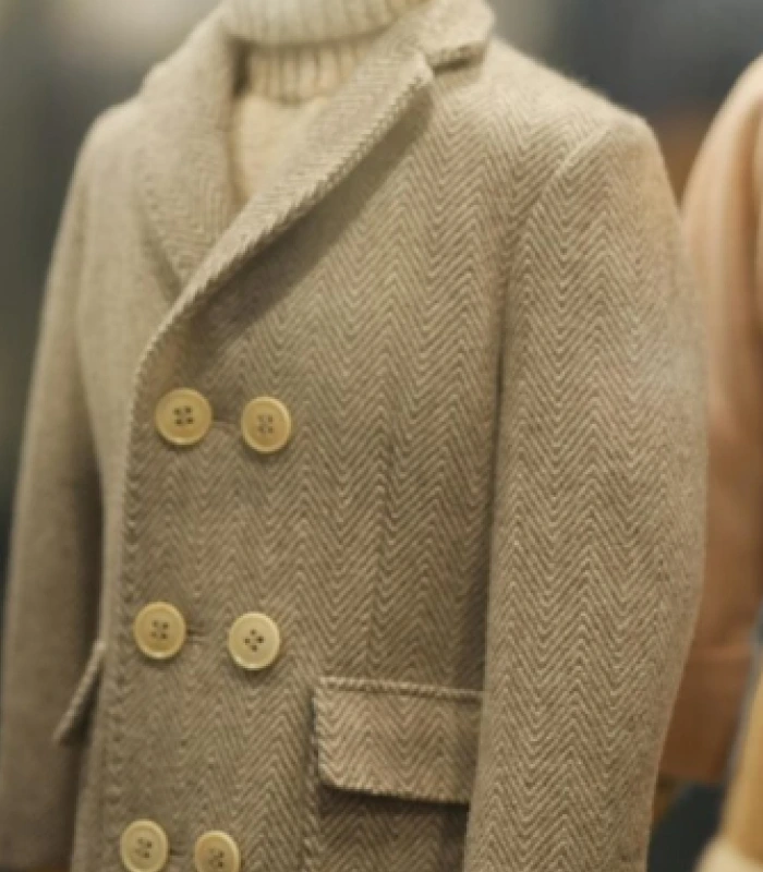 Close-up of a thick grey or beige wool peacoat featuring a prominent herringbone tweed weave