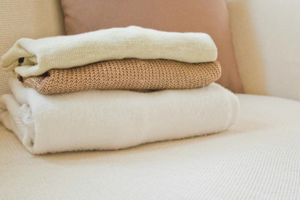 Stack of folded wool or cashmere knitwear in cream and beige