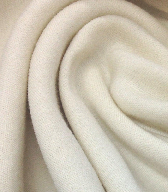 Spool of fine wool yarn resting on a soft, draped fleece or wool fabric